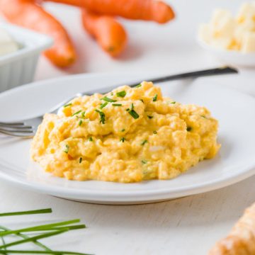 fresh scrambled eggs on white plate on breakfast table